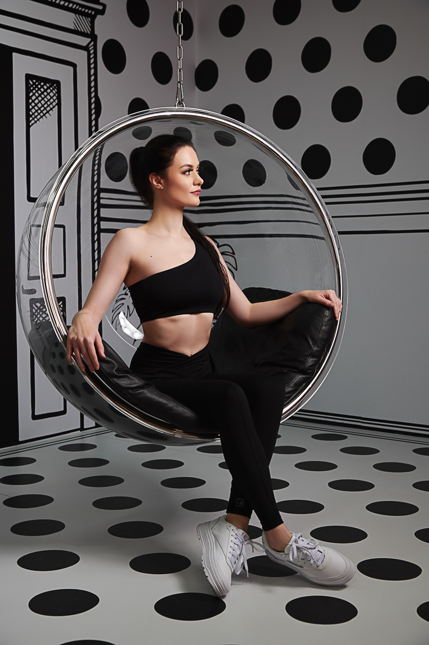 Elena Biedert sitting in a bubble chair in a black and white interior
